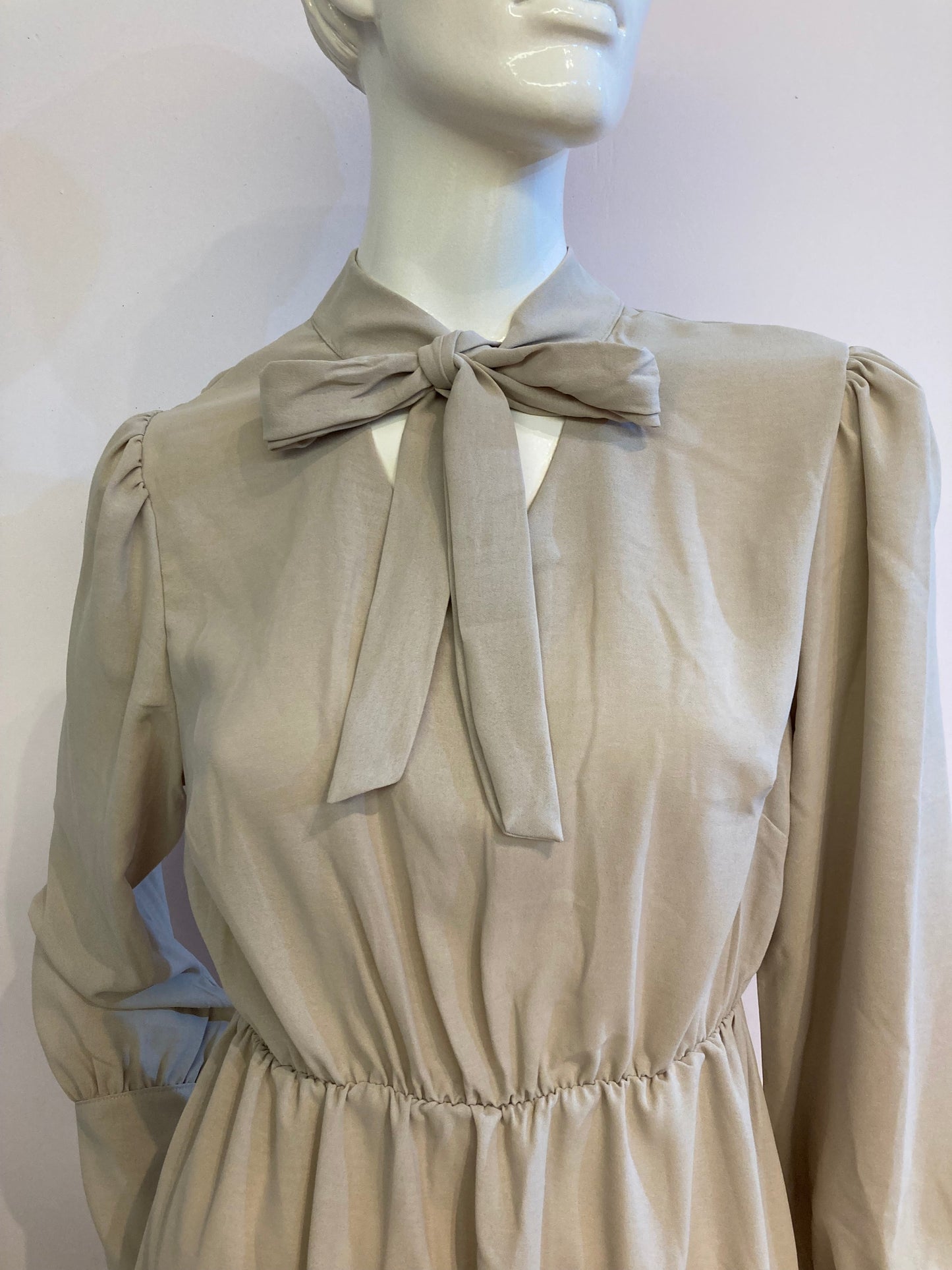 Beige skater dress with ruffle and knot at the neck